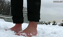 热情而性感的女人在雪地上赤裸着脚走着
